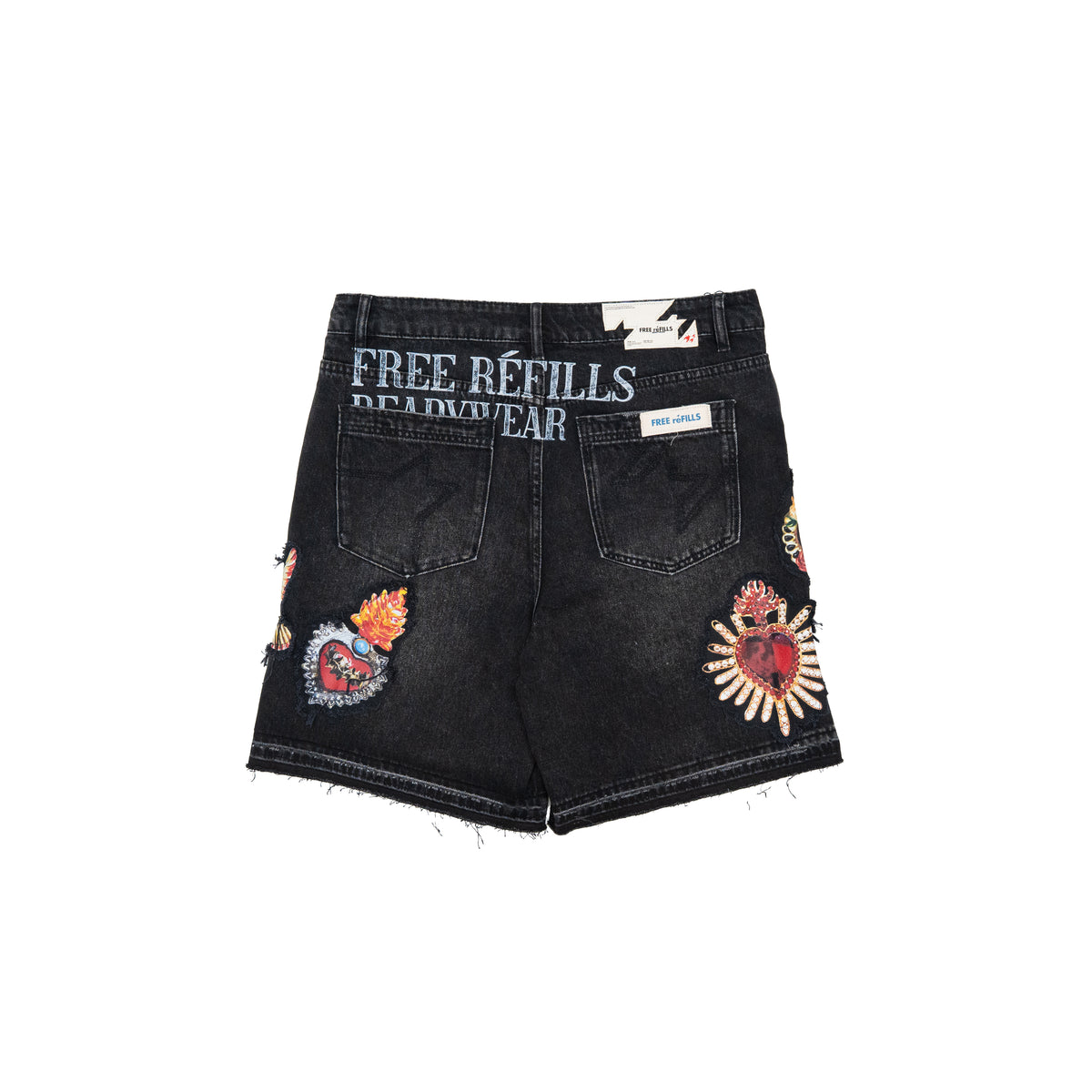 Black denim shorts with distressed frayed hems, featuring colorful embroidered heart and floral patches on the back pockets and side seams, and 'FREE REFILLS READYWEAR' printed in white on the back waistband.