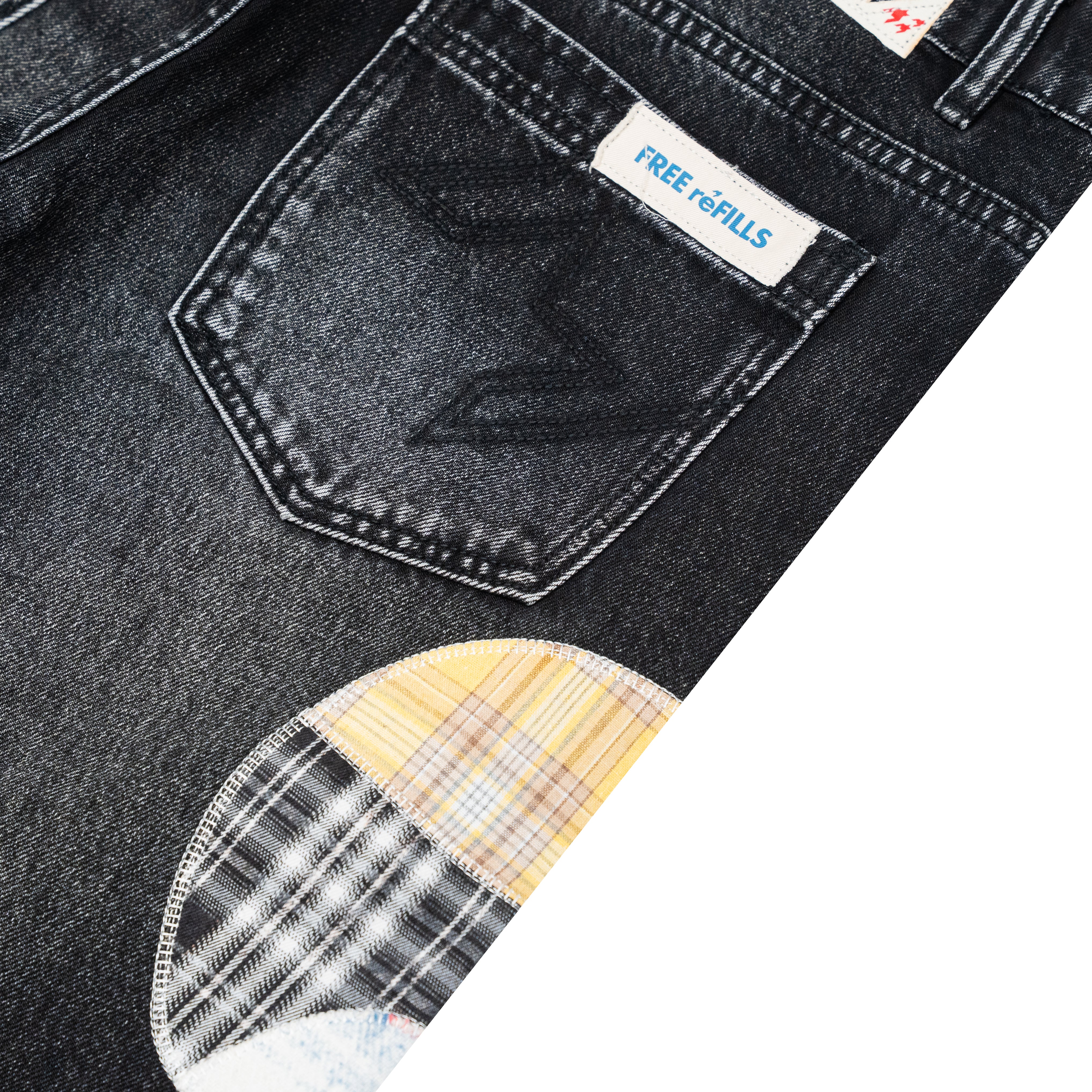 Close-up of dark washed denim jeans showing the back pocket with a visible FREE REFILLS label and a plaid patch detail near the lower left.