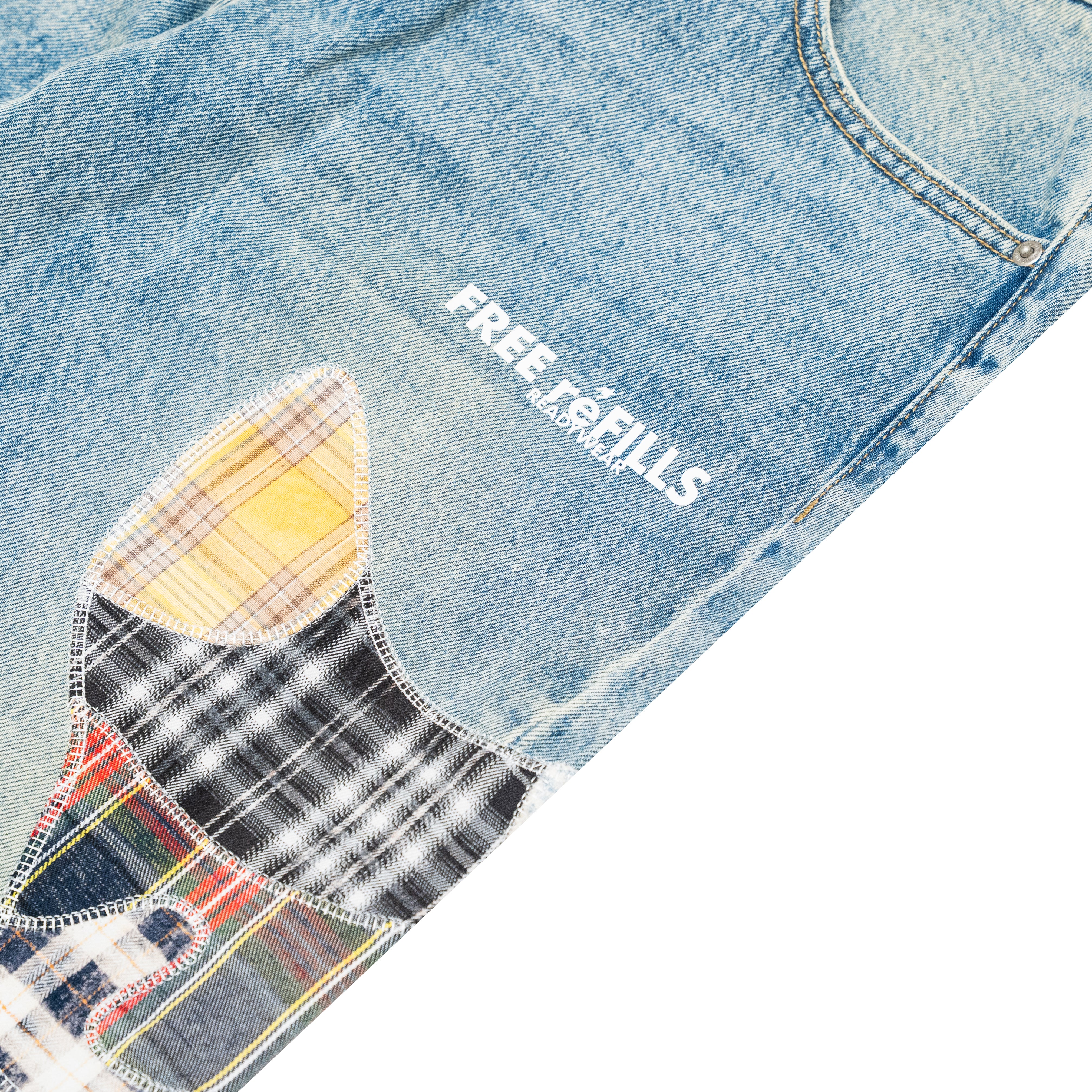 Close-up of light blue denim jeans with a large multicolor patchwork applique on the leg and white 'FREE REFILLS' text printed on the thigh.