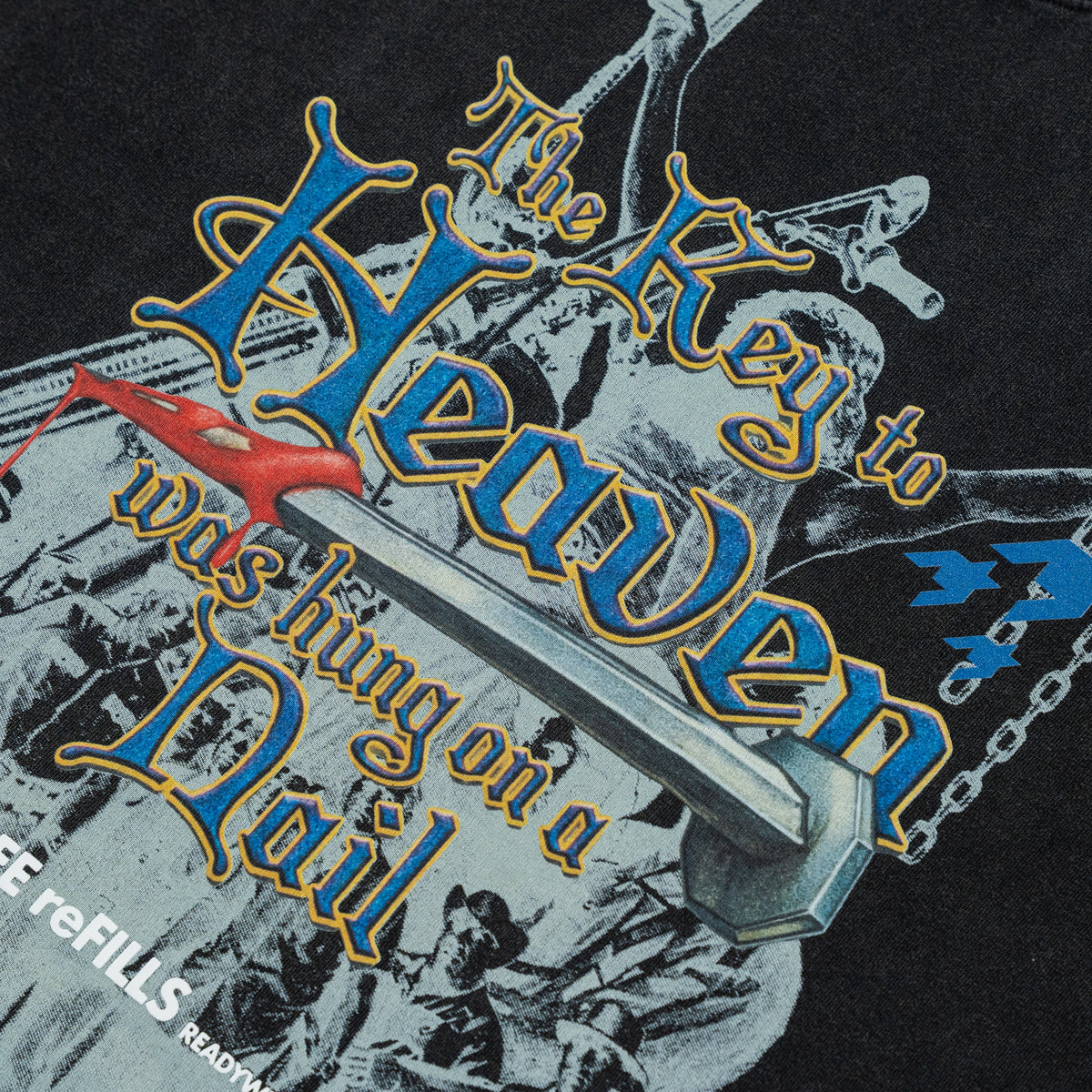 Close-up of a graphic print featuring the words 'The Key to Heaven was Hanging on a Nail' in stylized blue and gold lettering over a black background with grayscale imagery and a small red bird.