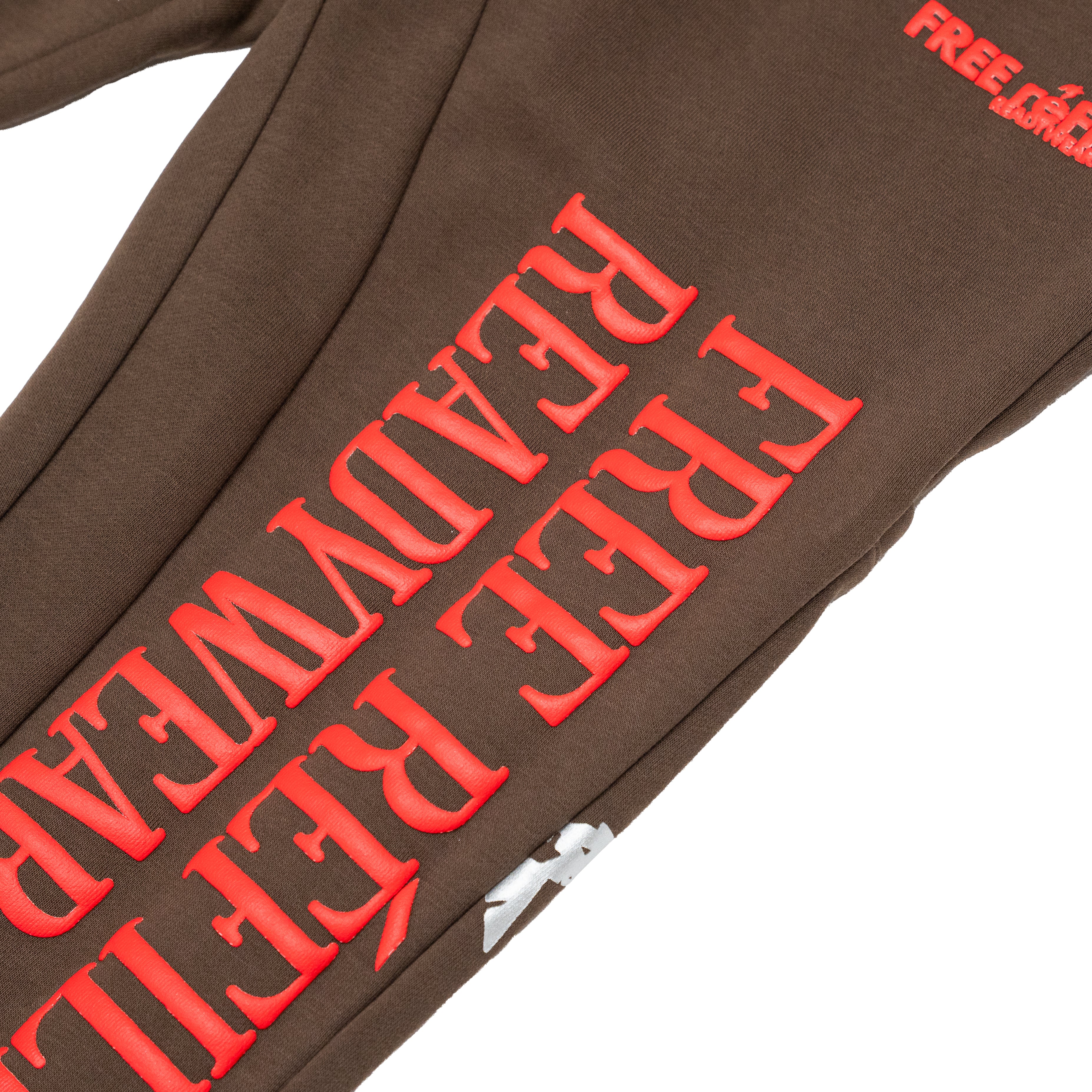 Close-up of a brown sweatpant leg with large red raised text reading 'FREE READYWEAR' and a small red 'FREE REFILLS