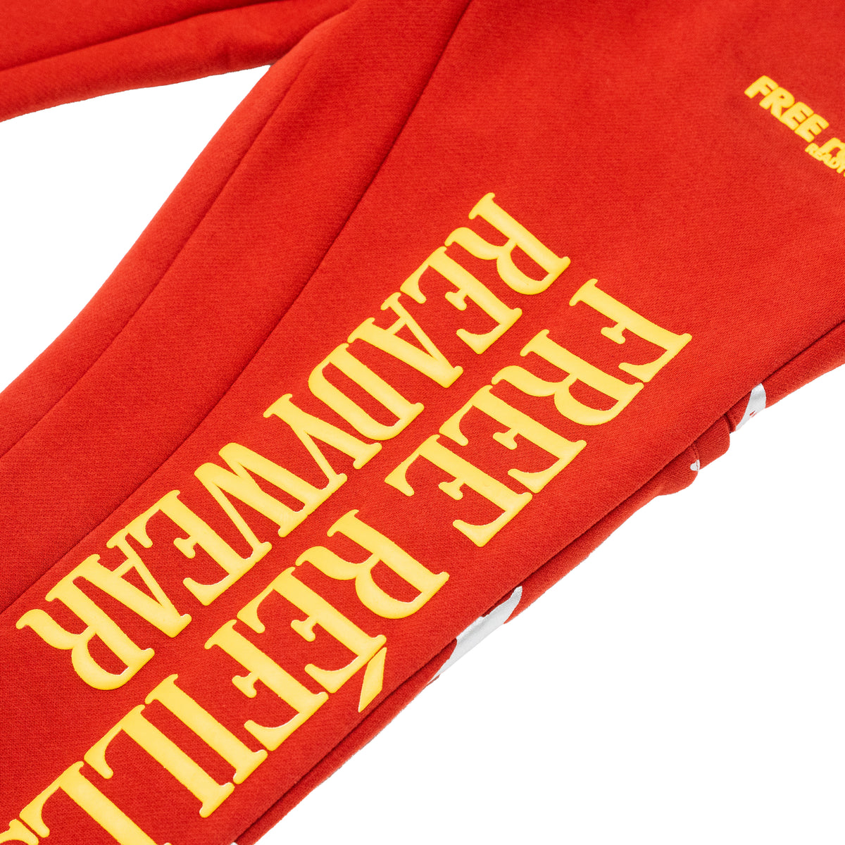 A close-up of a red sweatshirt or hoodie sleeve with large yellow text reading 'FREE REFILLS READYWEAR' and a small yellow 'FREE' mark near the top right, shown on a white background.