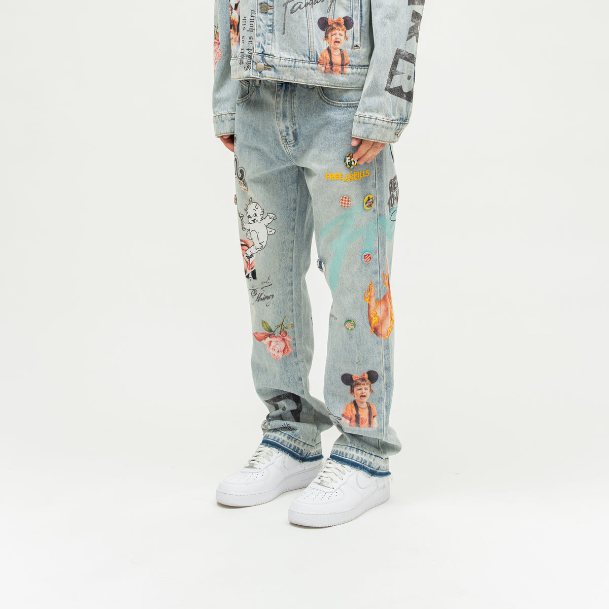The Powder Room Jeans – Blue – Angled view on model showing colorful leg graphics and decorative pins
