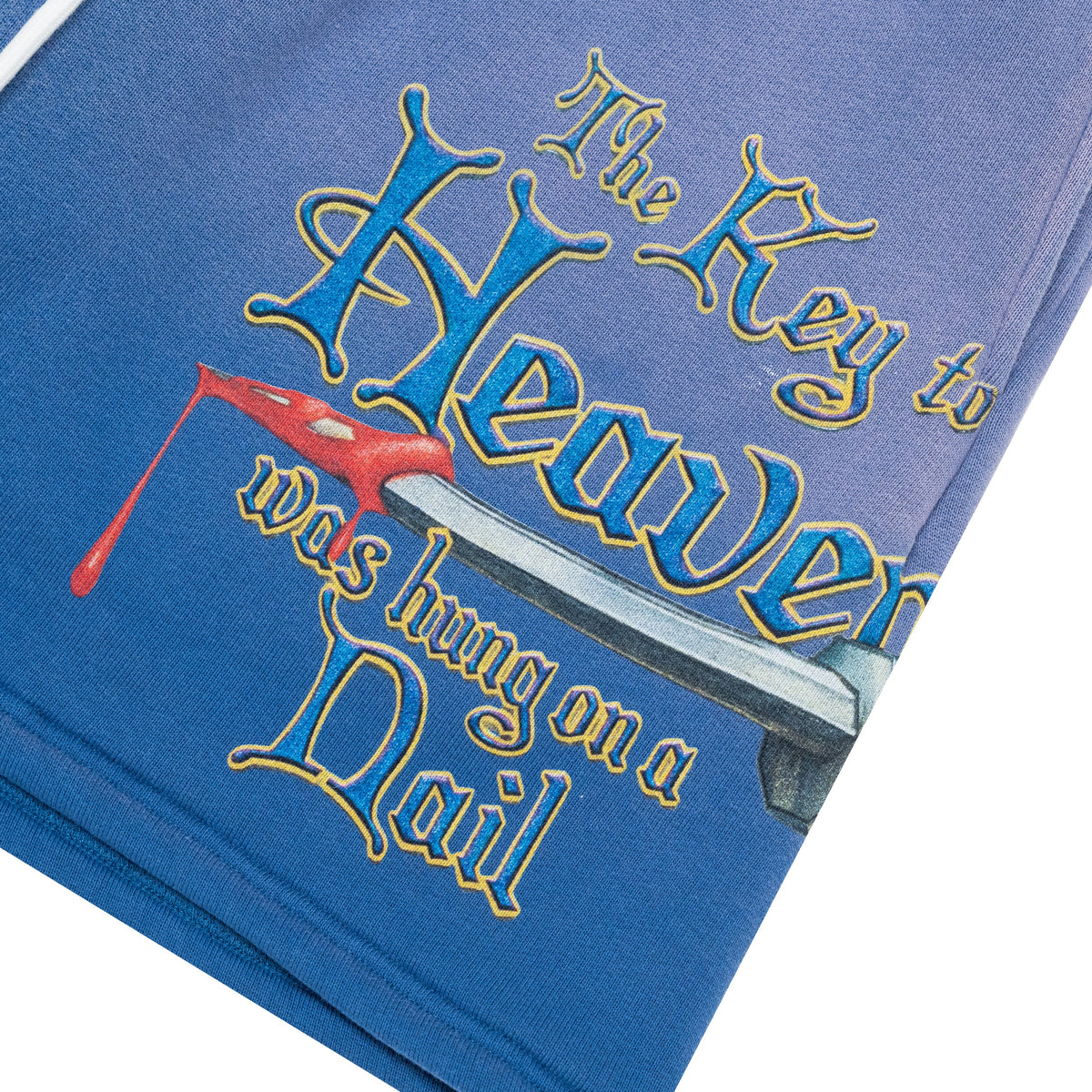 A close-up of a blue graphic t-shirt featuring the text 'The Key to Heaven was hung on a Nail' in stylized blue and gold lettering with a red nail illustration.