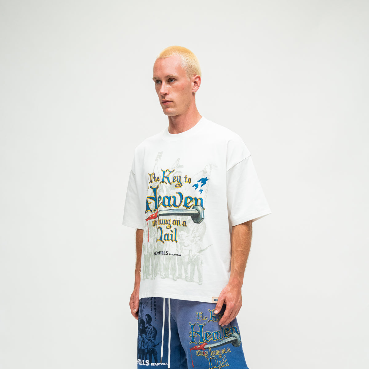 A man wearing a white graphic t-shirt with 'The Key to Heaven was hanging on a Nail' text and 'FREE REFILLS' branding.