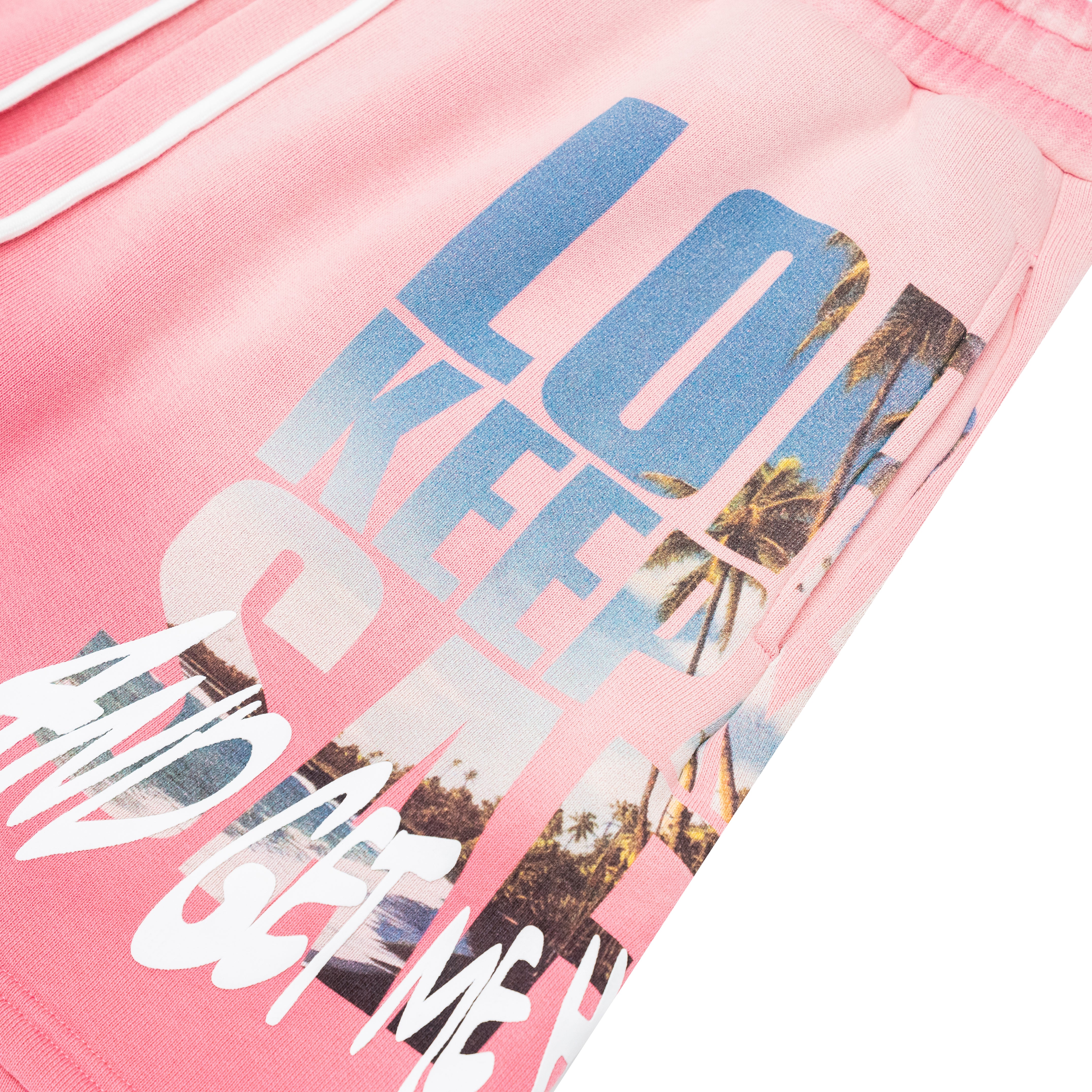 Pink sweatpants featuring a large graphic print with the words 'LOVE KEEP ME SAFE' in blue, white, and palm tree beach scene imagery.