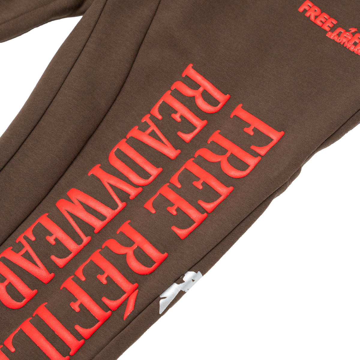 Close-up of a brown sweatpant leg with large red raised text reading 'FREE READYWEAR' and a small red 'FREE REFILLS
