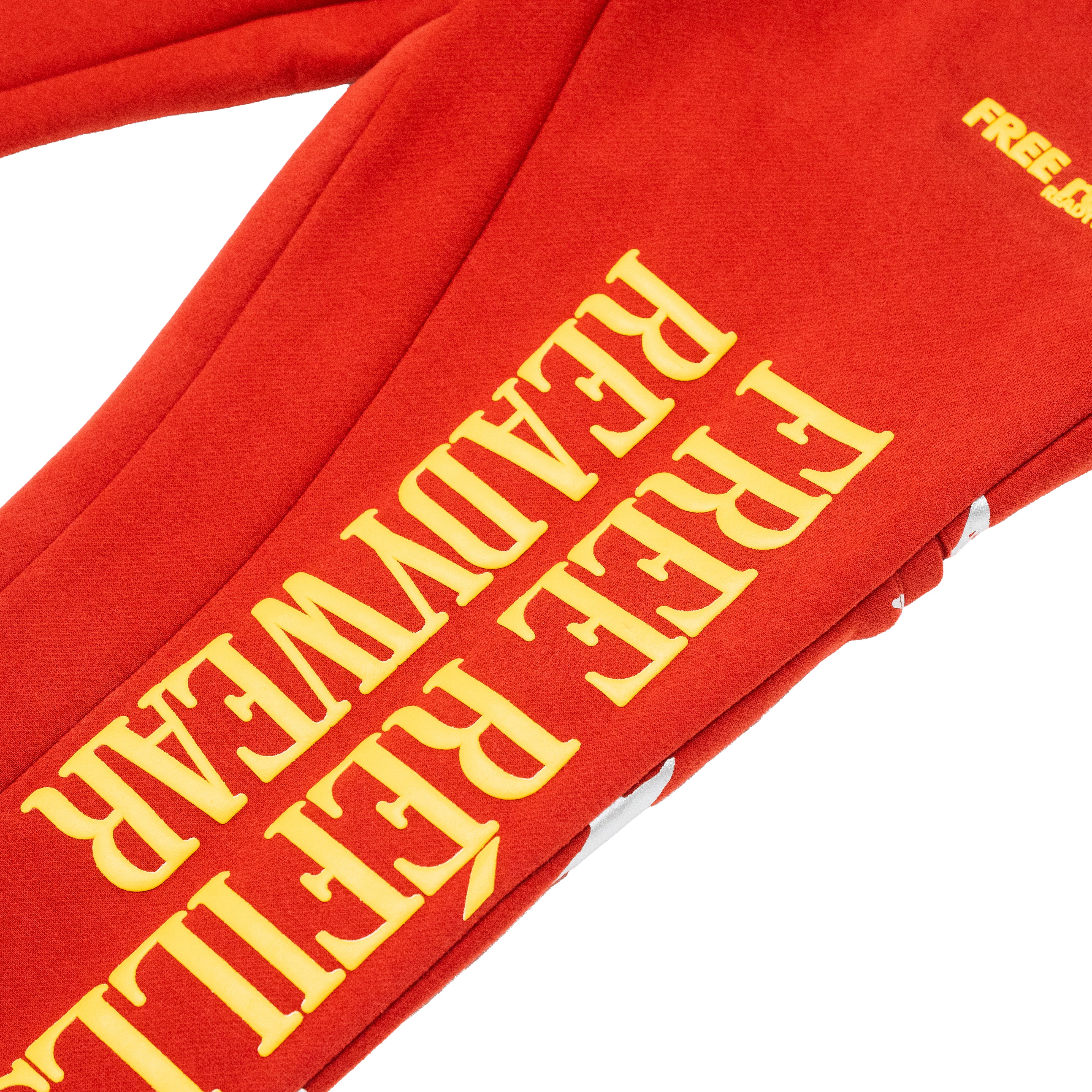 A close-up of a red sweatshirt or hoodie sleeve with large yellow text reading 'FREE REFILLS READYWEAR' and a small yellow 'FREE' mark near the top right, shown on a white background.