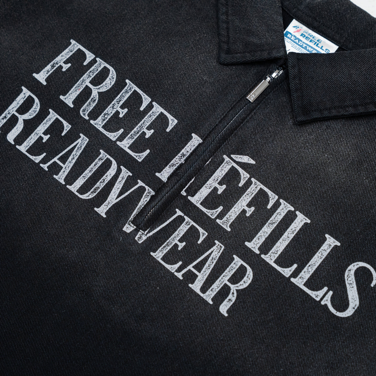 Close-up of a black zippered pullover shirt with large distressed white text reading 'FREE REFILLS READY WEAR' across the chest and a visible neck label.