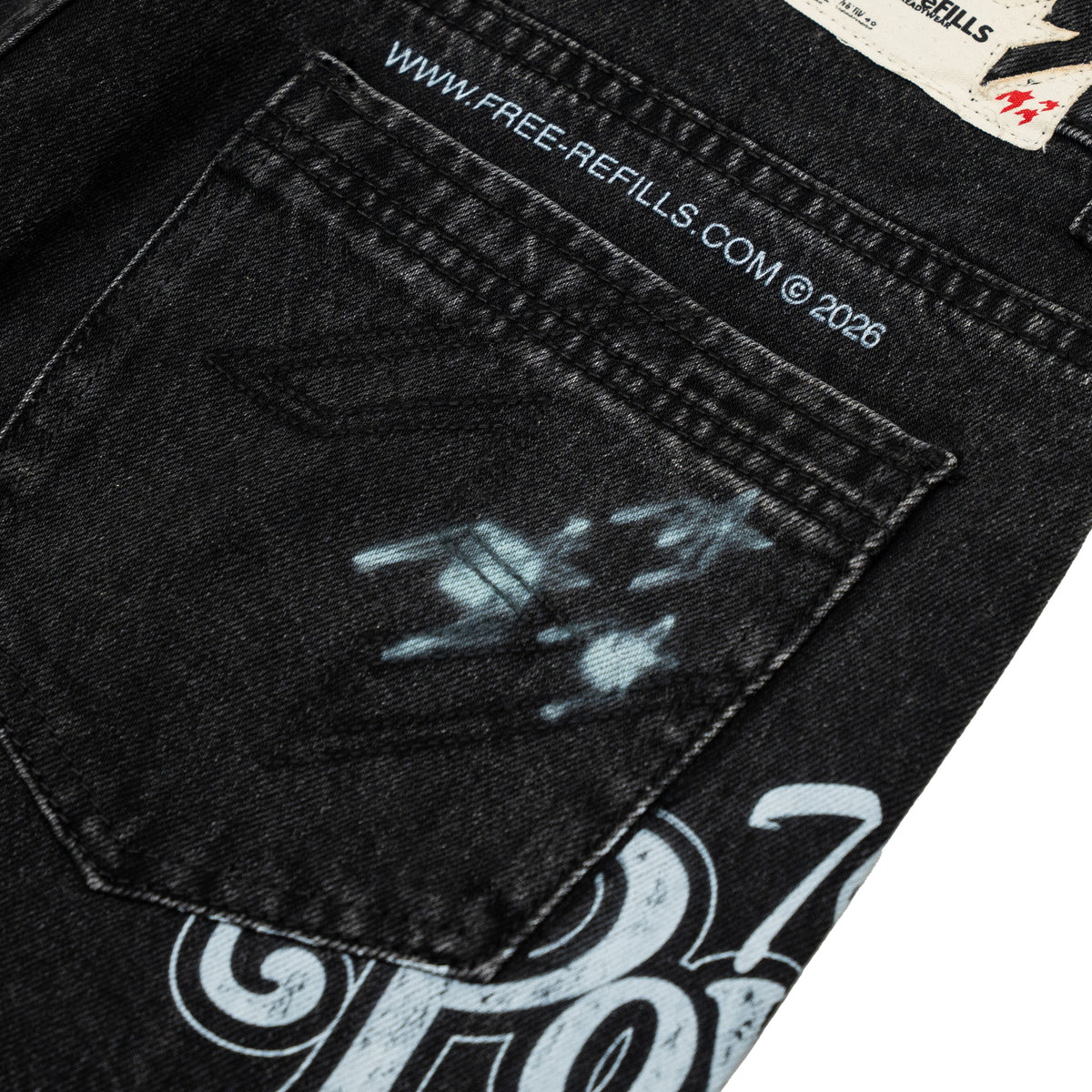 The Powder Room Jeans – Black – Close-up of back pocket with faded graphic and printed website text