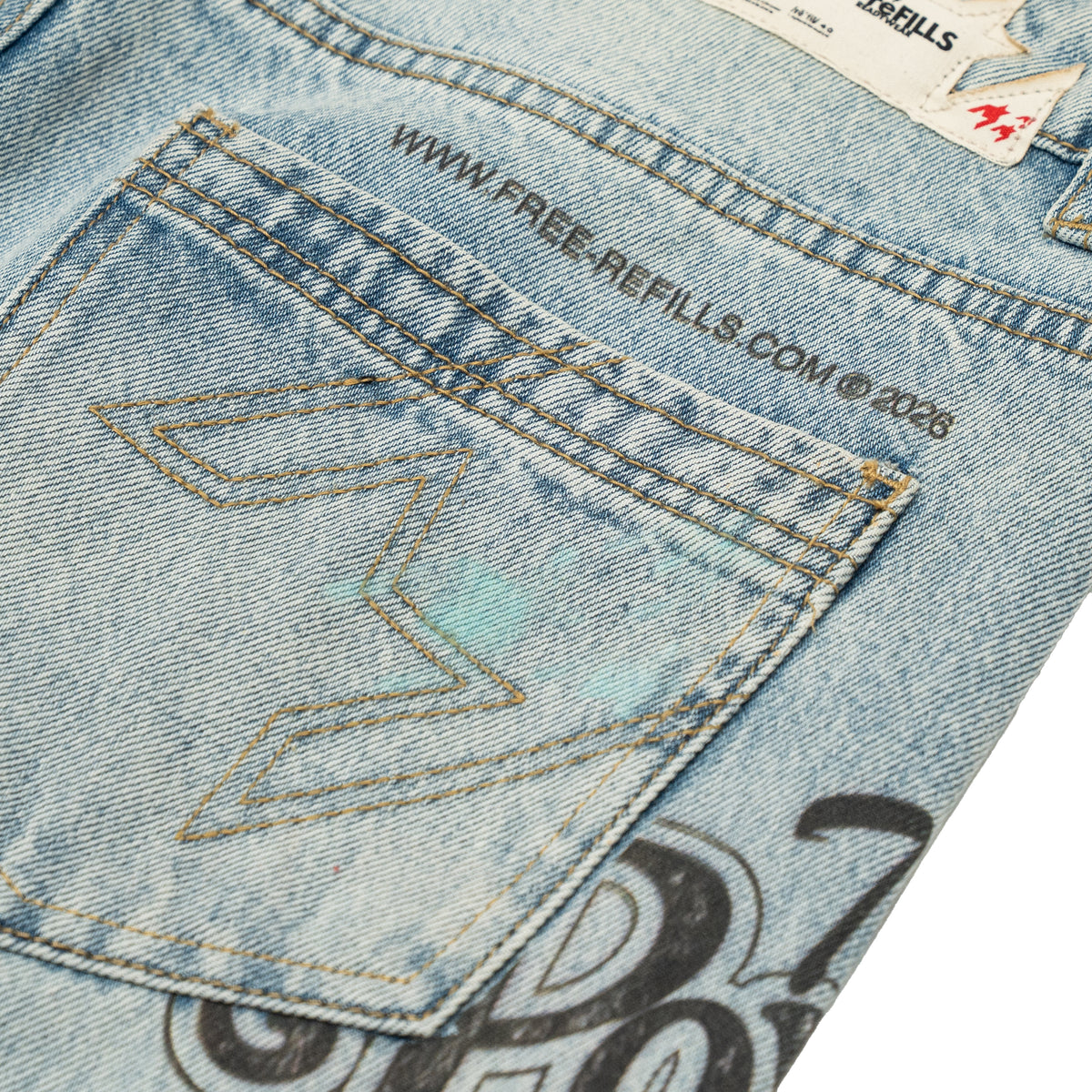 The Powder Room Jeans – Blue – Close-up of back pocket with angular stitching and printed website text